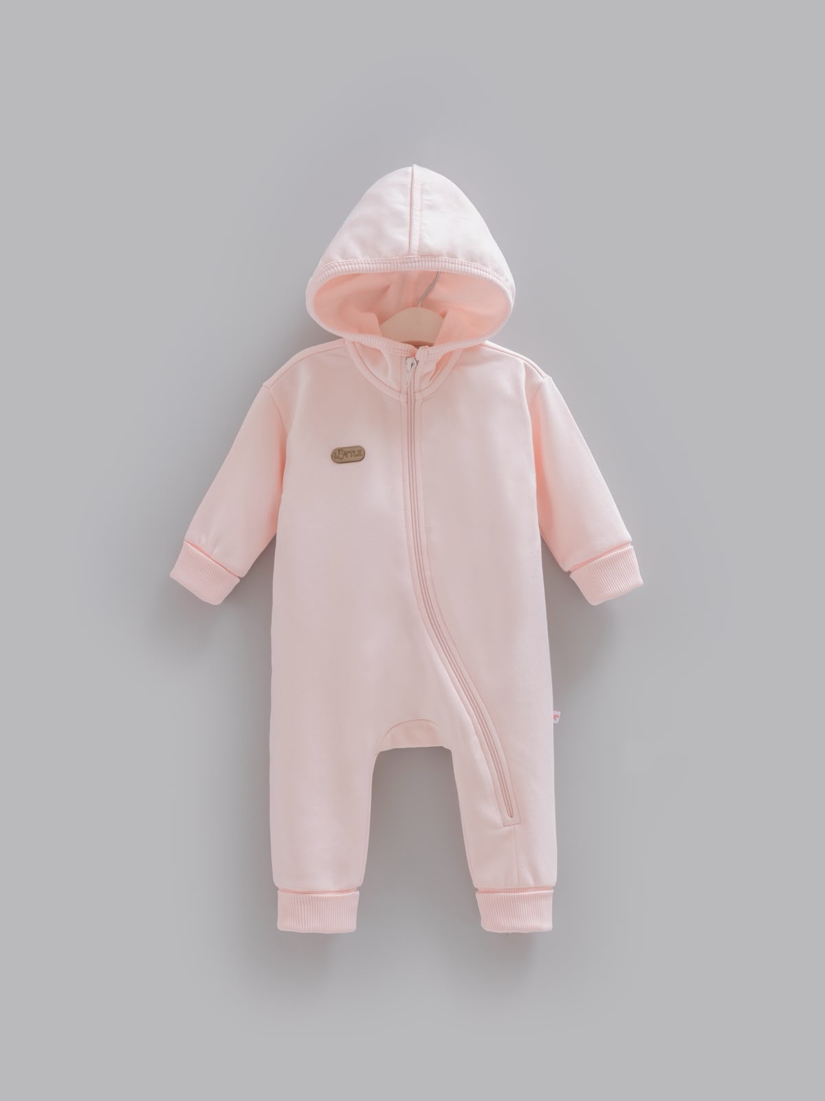 Açık pembe, kapüşonlu, önden paçaya uzanan fermuarlı, kol ve paça uçları ribanalı pamuklu kız bebek tulum.
